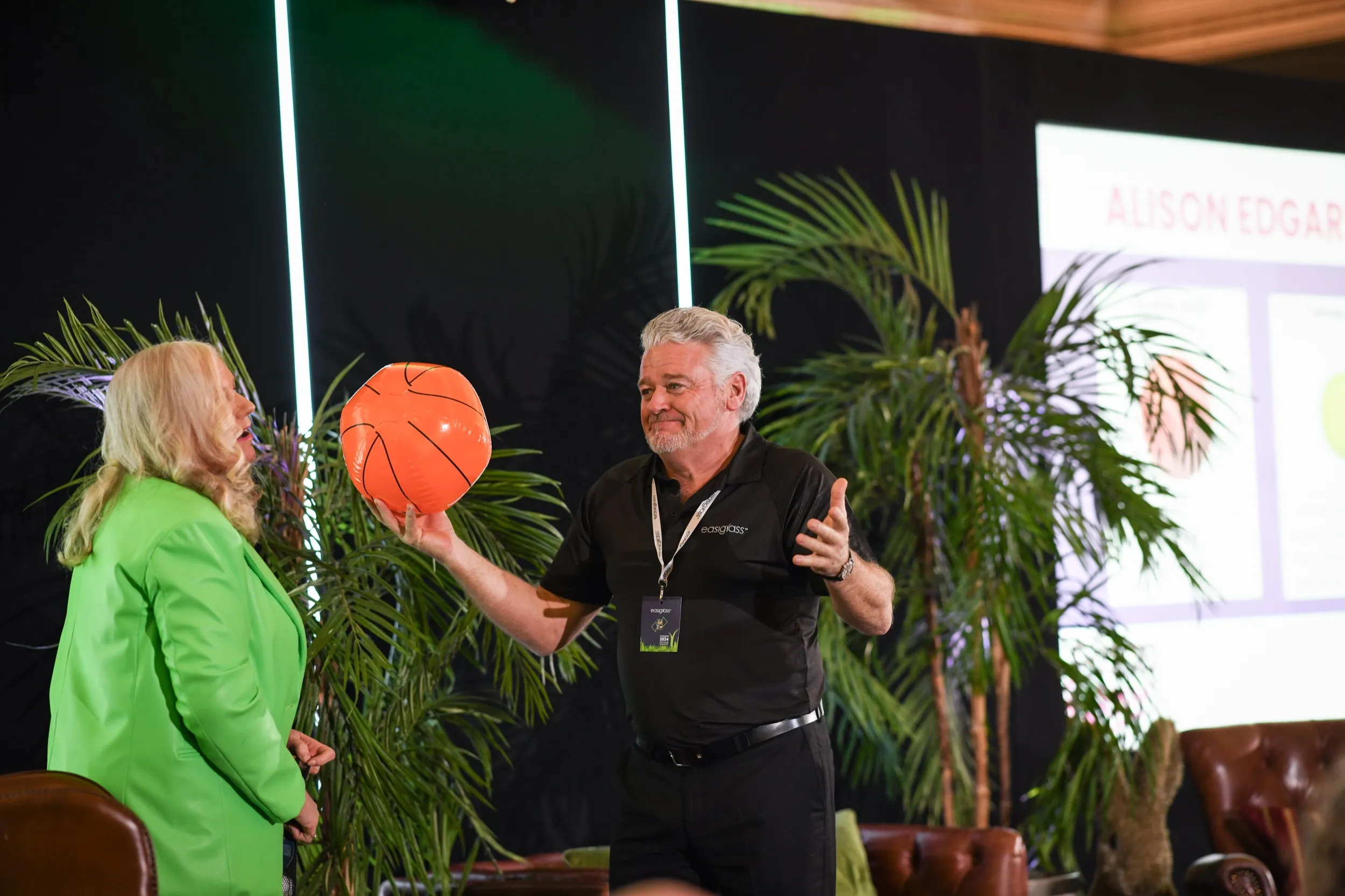 Alison mid-exercise on a client's stage, a volunteer's arms full of Big Balls.