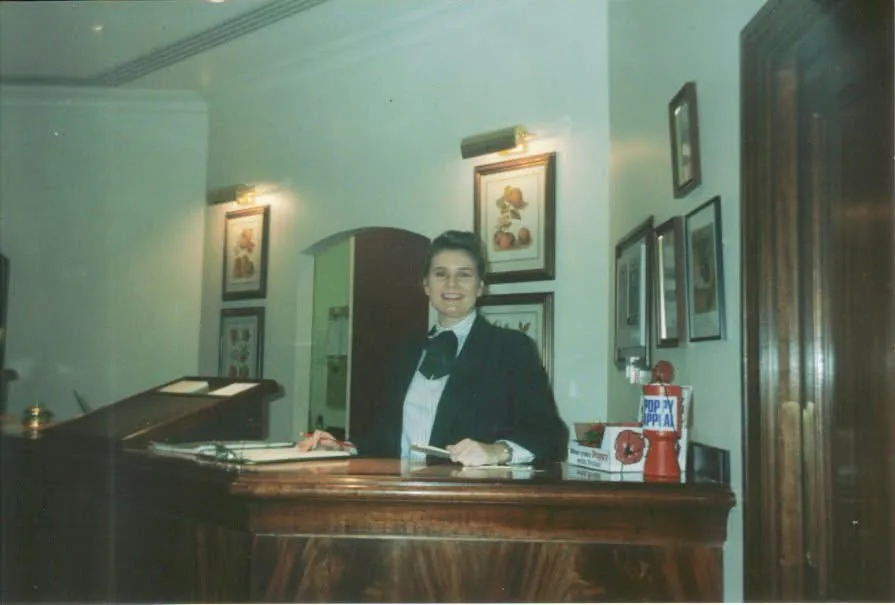 A young Alison in uniform behind the reception desk of the hotel where she started.