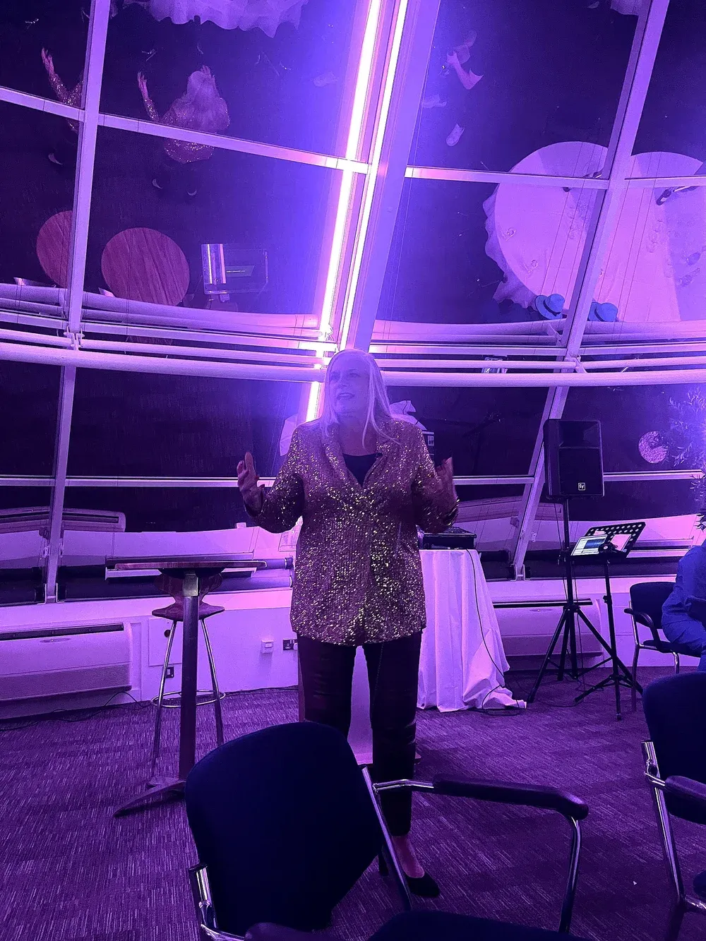 Alison delivering her slide-less keynote in a gold sequin jacket.
