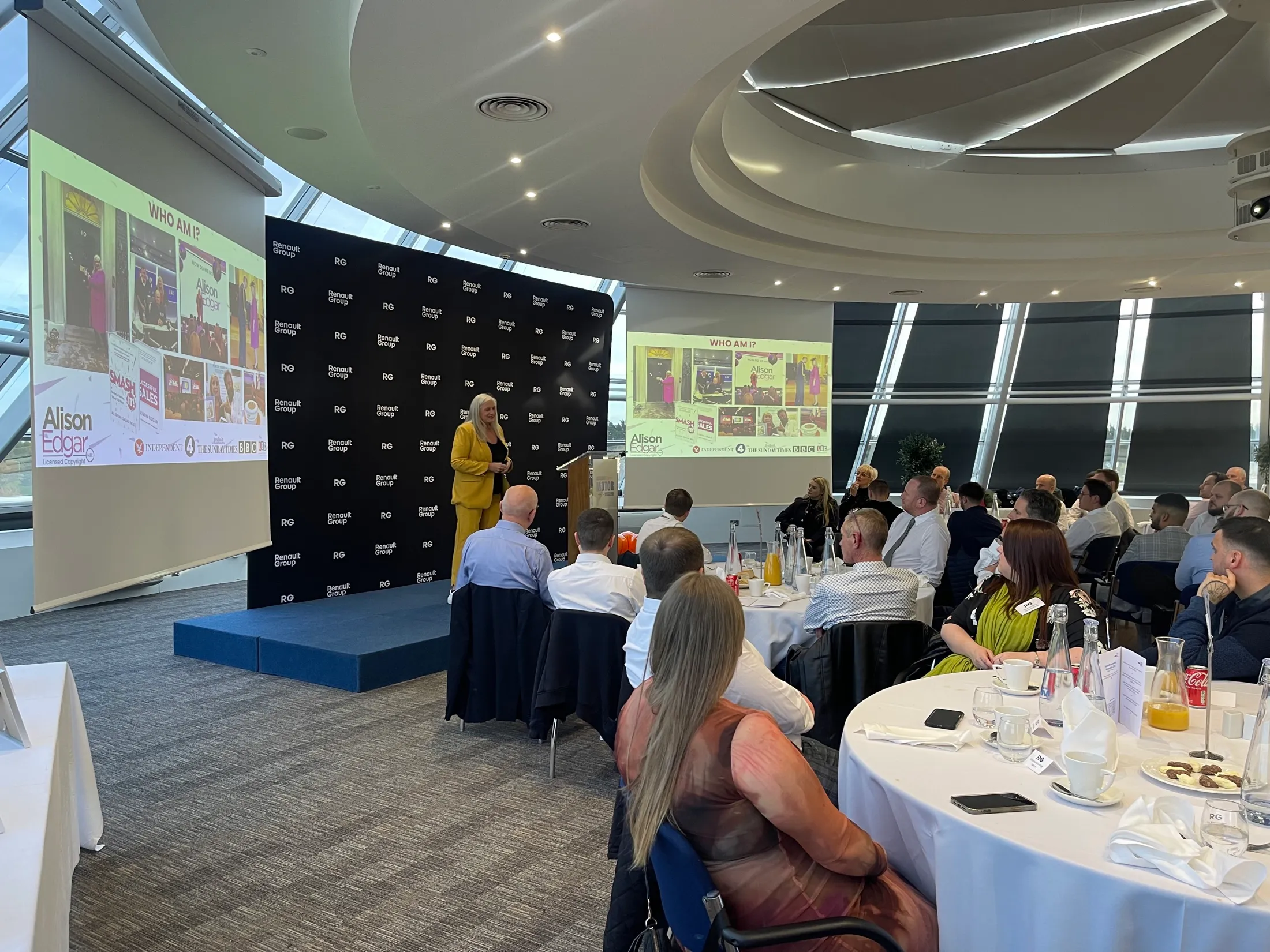 Alison on stage at the British Motor Museum, her slides on twin screens as Renault's apprentice graduates look on.